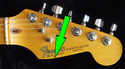 The headstock of a 1990 American Standard Stratocaster. Its shape was often called pregnant due to the pronunced curve indicated by the green arrow. The serial number was black.