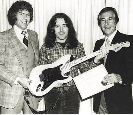 Rory Gallagher con la sua nuova Stratocaster del venticinquesimo anniversario insieme ai rappresentanti Fender nel 1979